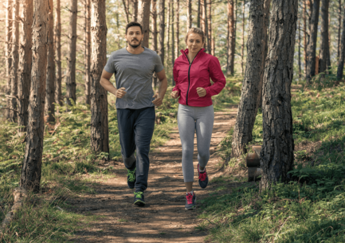 Mann und Frau joggen gemeinsam durch den Wald als Beispiel eines nachhaltigen Benefits